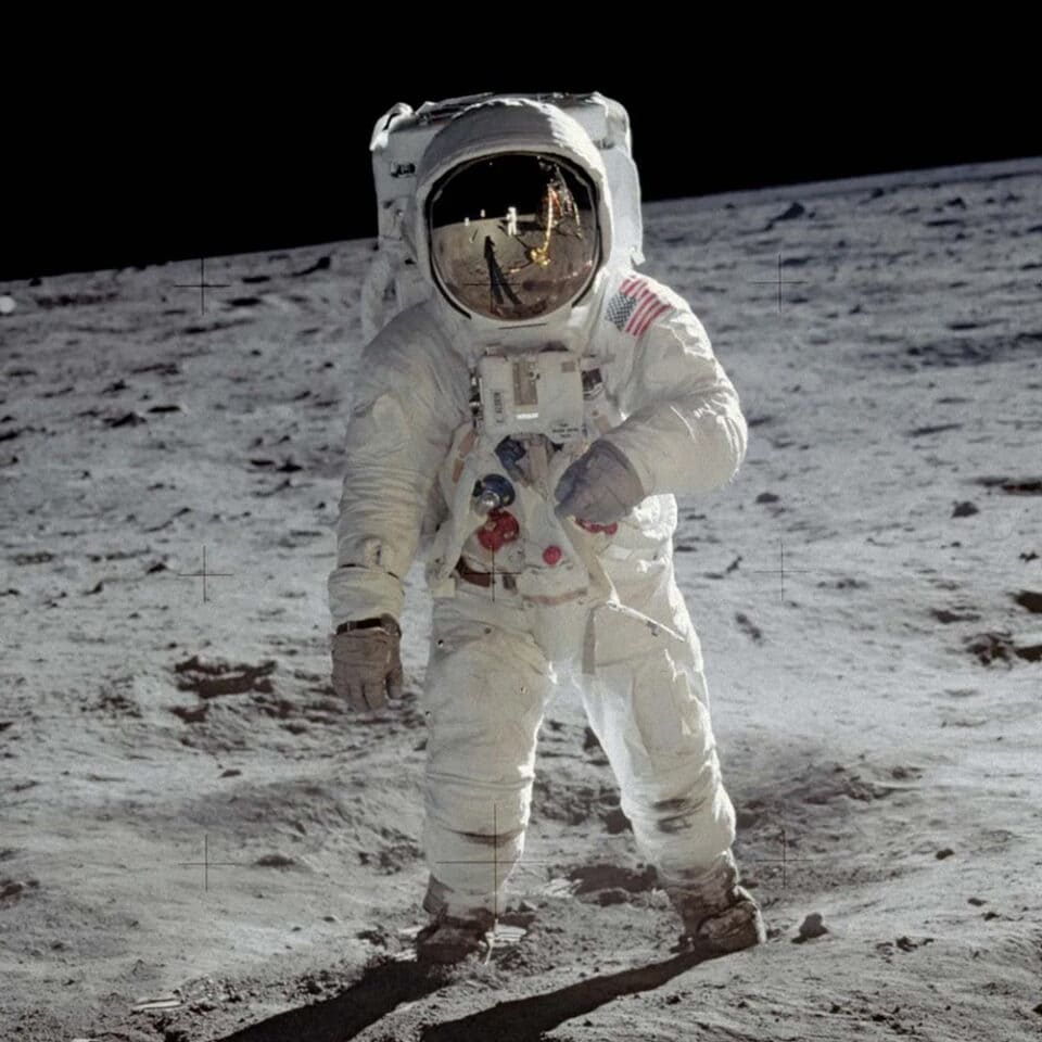 Astronaut Andrew von Gregor on the moon's surface, wearing a spacesuit and helmet, with the lunar landscape and black sky in the background.