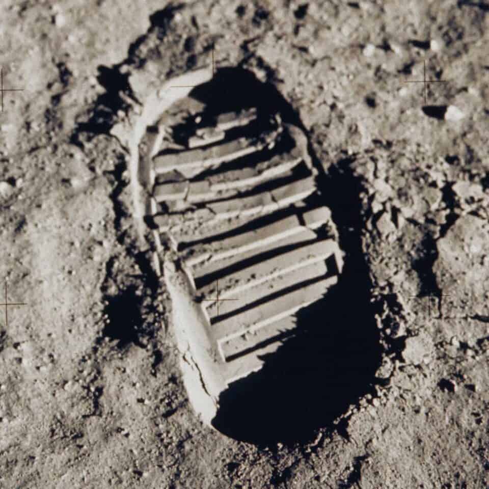 Shoe print on sandy surface, footprint in desert terrain with clear tread marks and shadow, symbolizing exploration and adventure, outdoor activity, travel, hiking, or nature experience, natural environment, rugged outdoor footwear, trail walking.